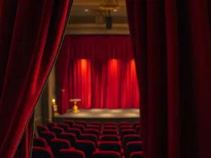 Szczegółowa makieta sceny teatralnej z oświetleniem i kurtynami, wykonana ręcznie na warsztatowym stole.